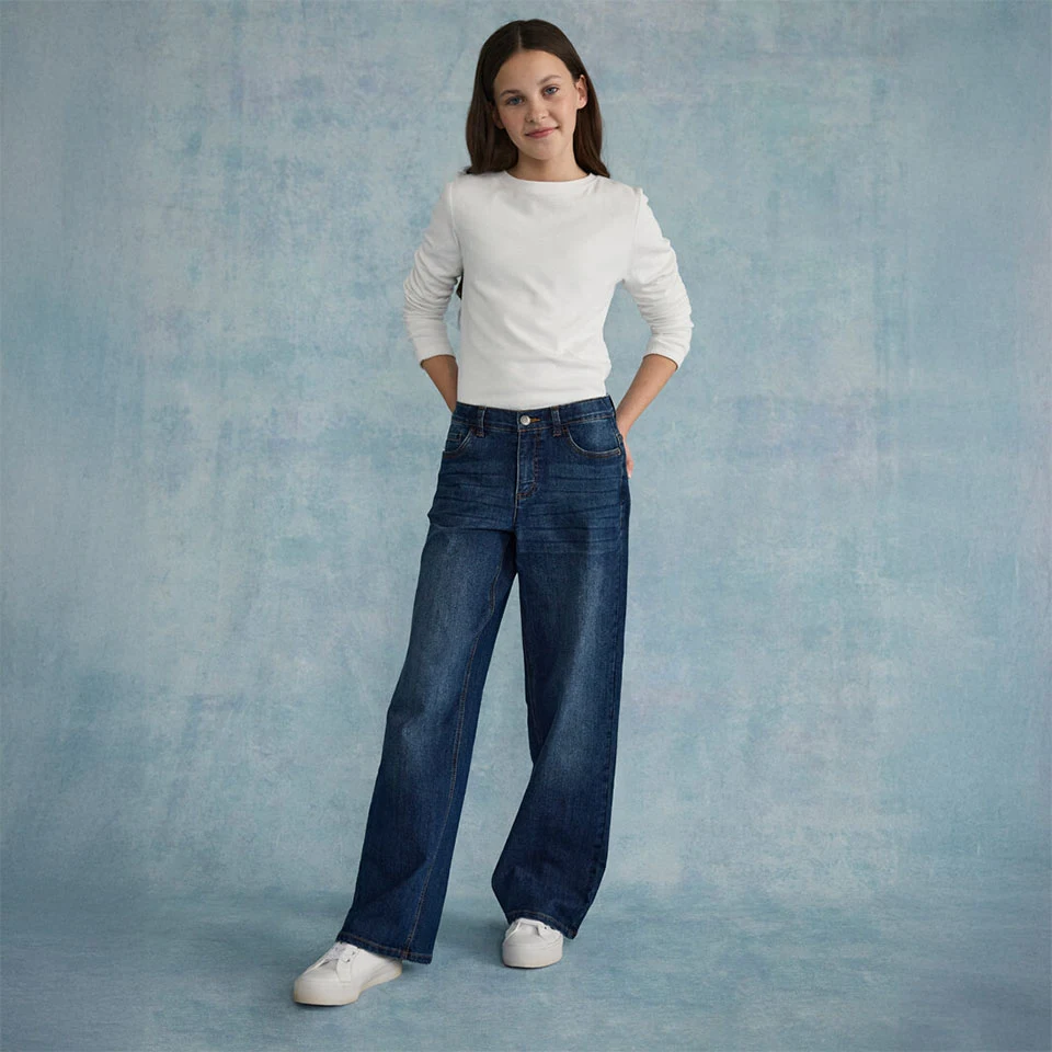 Witte, gestructureerde top gecombineerd met een wijde jeans en witte sneakers.