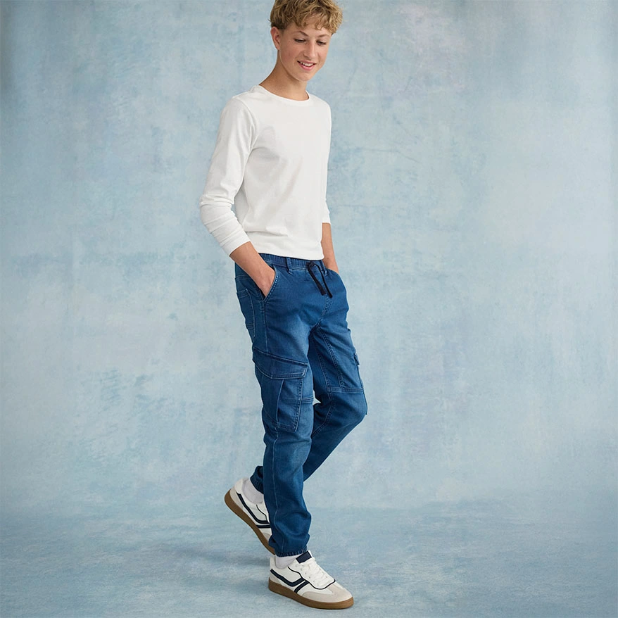 Casual look: witte trui met blauwe jeans en witte sneakers.