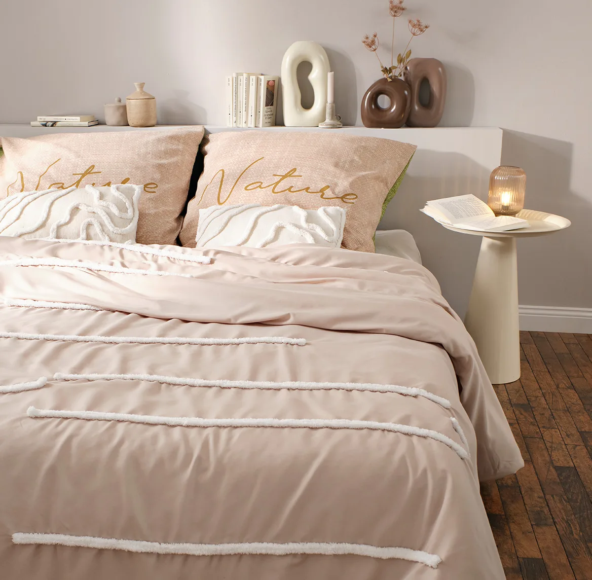 Lichtroze beddengoed met fijne strepen siert de gezellige slaapkamer in warme pasteltinten.