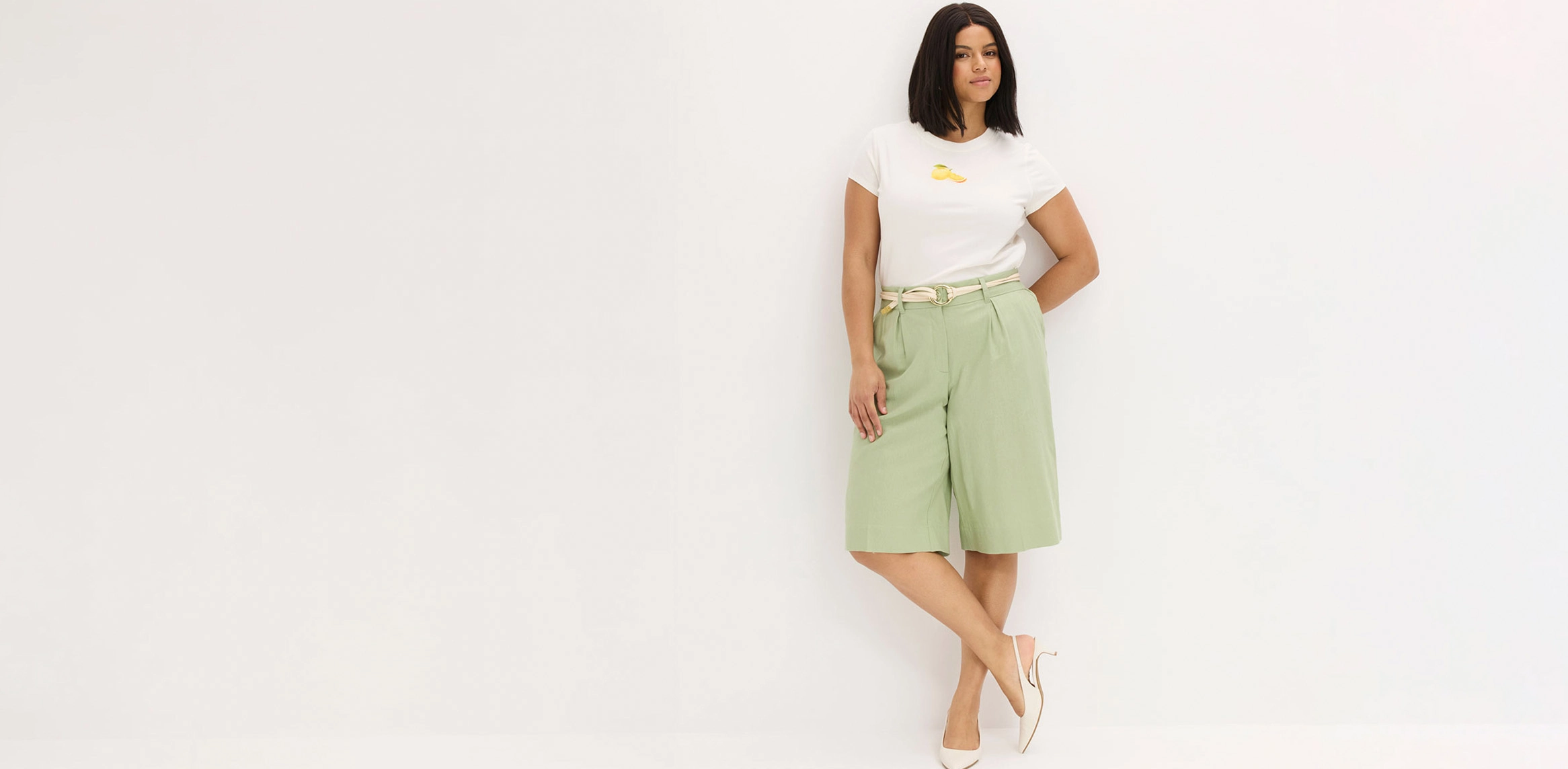 Wit T‑shirt, mintgroene bermuda en beige sandalen.