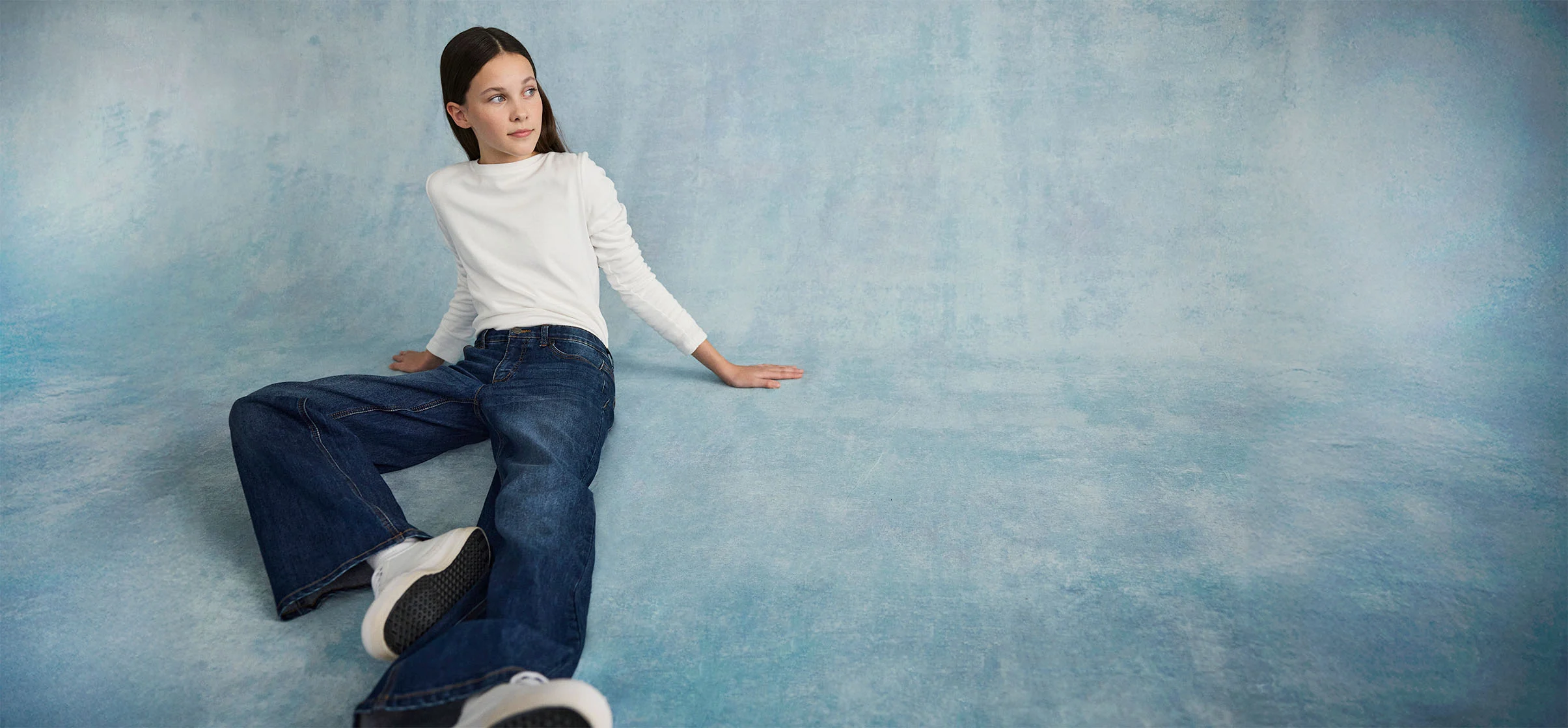Pull blanc et jean large : un look décontracté pour les journées de détente.