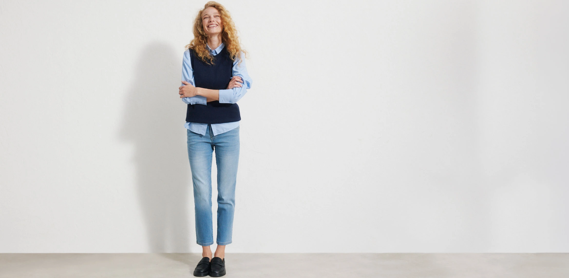 Lichtblauwe Straight‑Fit jeans met een hoge taille en een rechte, klassieke pijp, gemaakt van glad, licht verweerd denim, gecombineerd met een wit T‑shirt, een denimjas en bruine schoenen.