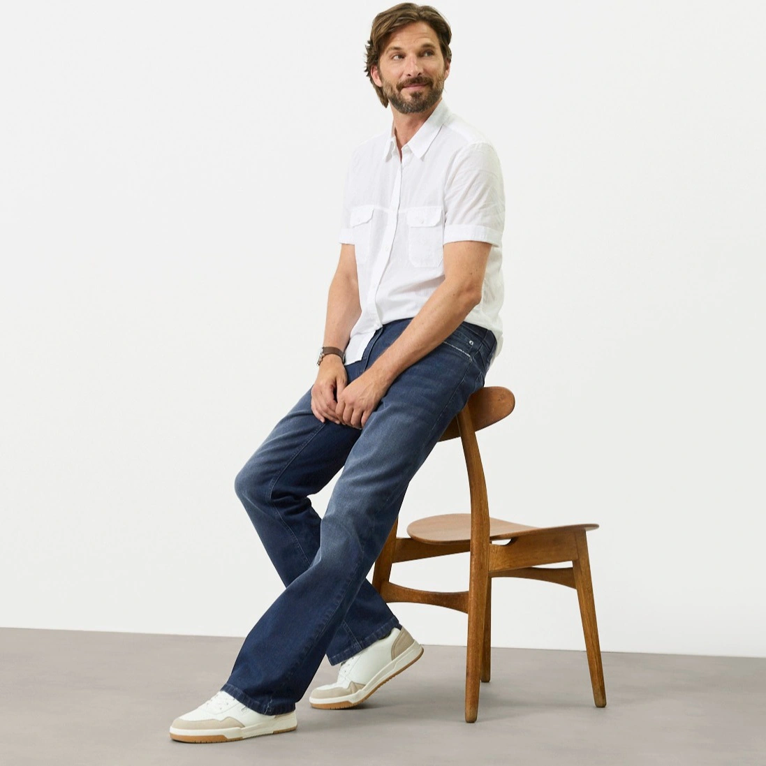Wit overhemd met korte mouwen, blauwe Regular Fit jeans en moderne witte sneakers.