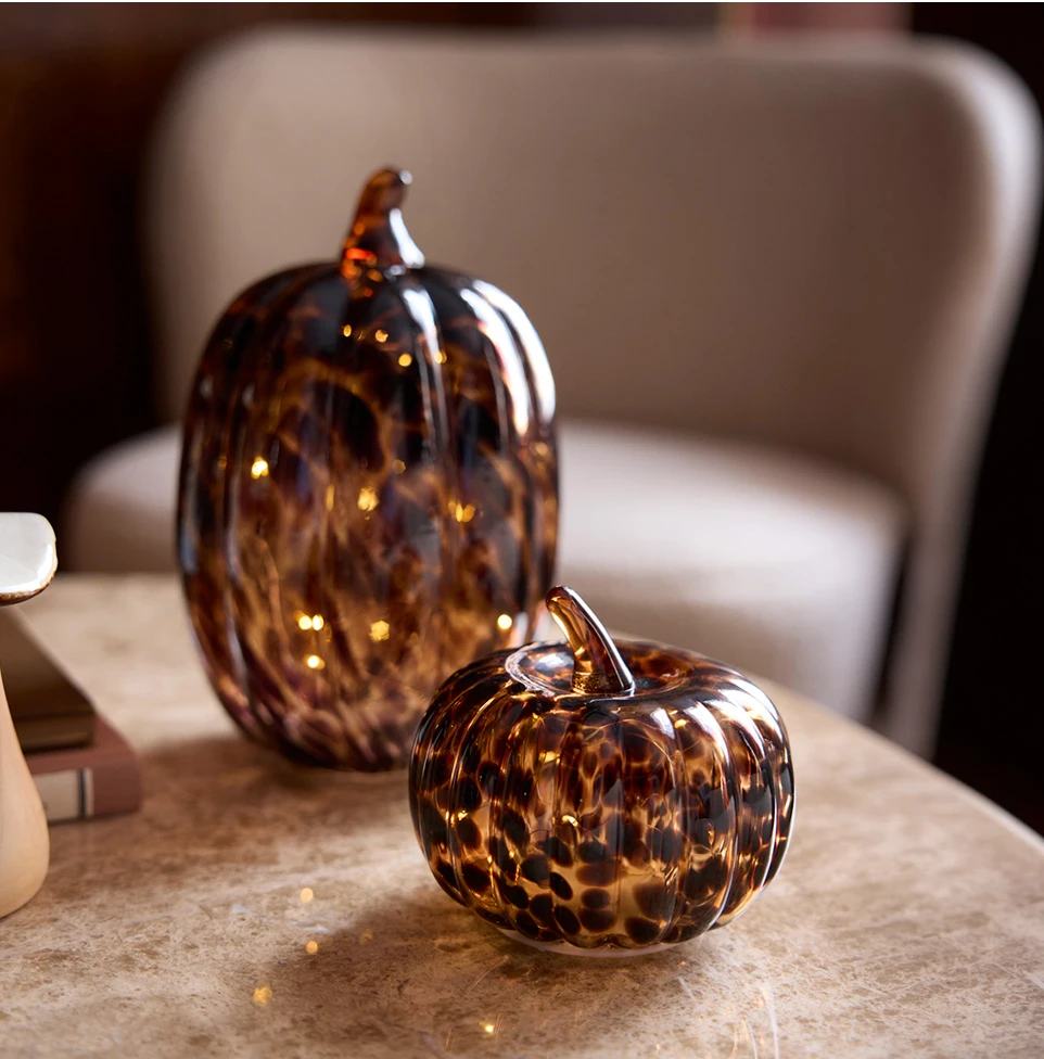 Decoratieve glazen pompoenen in amber- en bruintinten, ideaal voor herfstige interieurarrangementen.