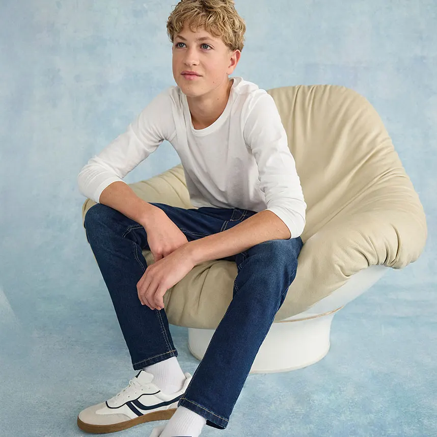 Witte longsleeve, donkere jeans en witte sneakers.