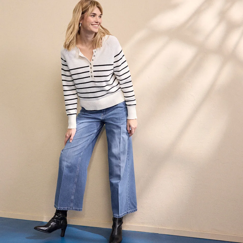 Witte gestreepte sweater met rits, gecombineerd met een wijde jeans en zwarte laarzen.
