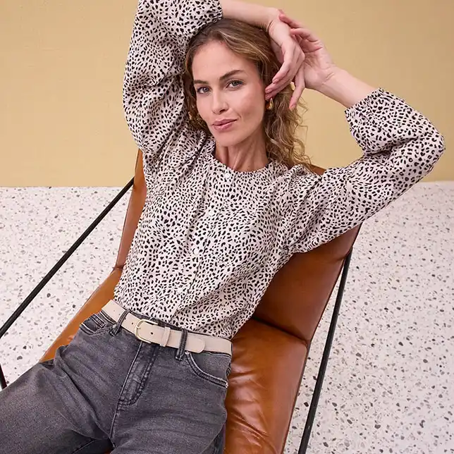 Blouse met stippen en lange mouwen gecombineerd met jeans en riem.