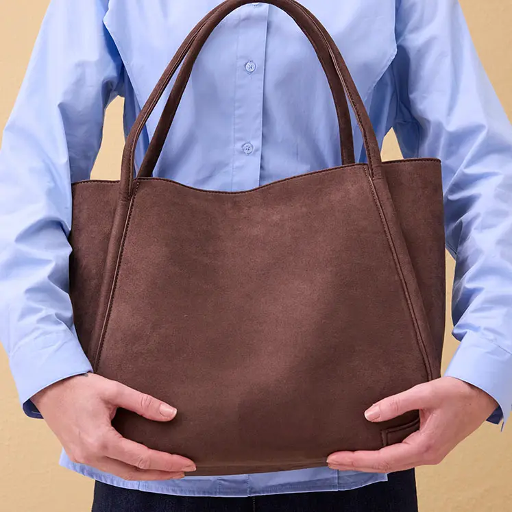 Lichtblauwe blouse en bruine imitatieleren tas.