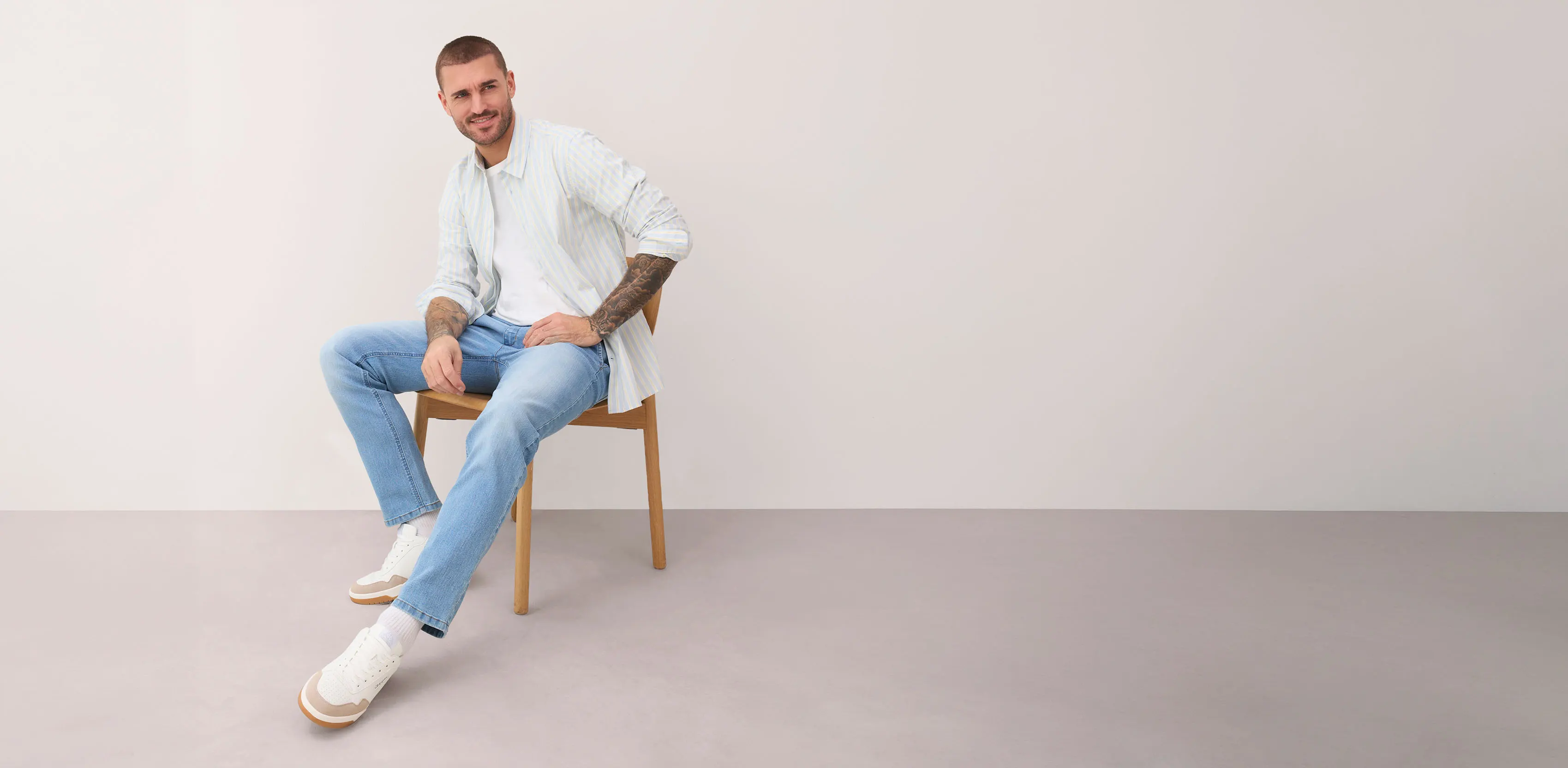 Wit, gestreept overhemd, lichtblauwe jeans en witte sneakers.