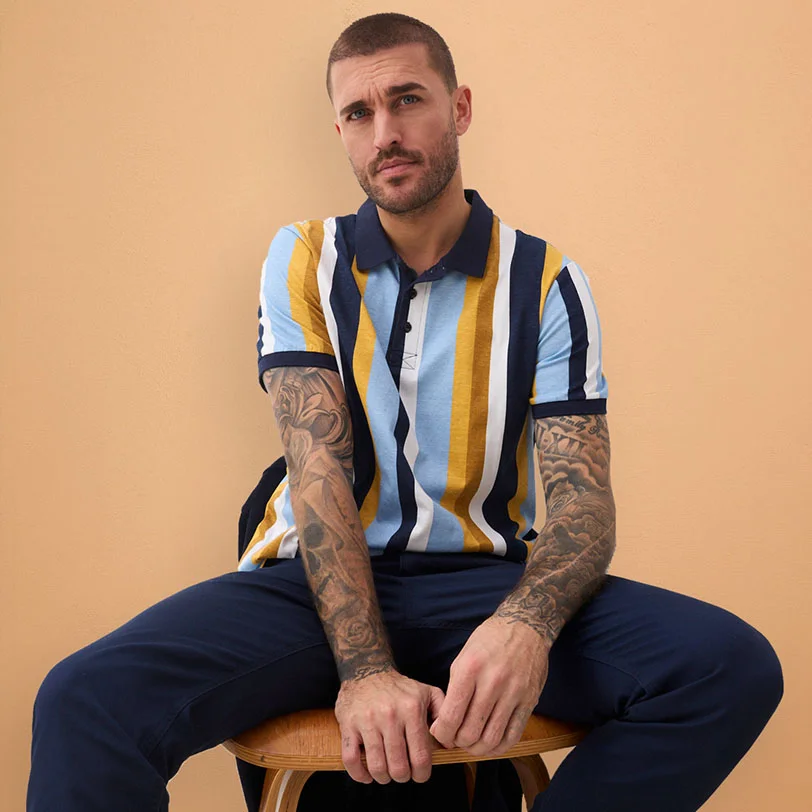 Perzikkleurig T-shirt gecombineerd met lichte broek en bijpassende trui als accessoire.