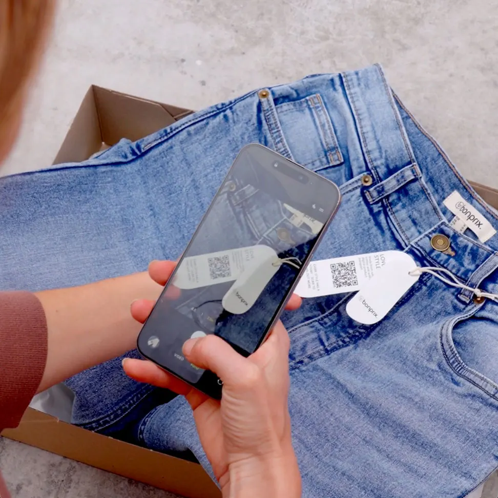 Blauwe jeans op grijze ondergrond. Handen houden smartphone over kleding.