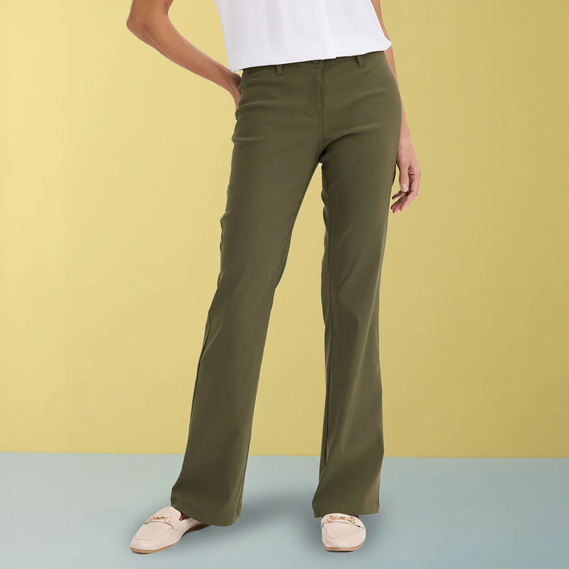 Elegante olijfgroene broek gecombineerd met witte top en beige schoenen.