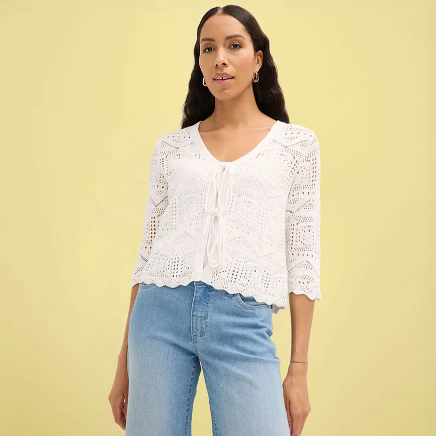 Wit gehaakt vest met halflange mouwen gecombineerd met blauwe jeans.