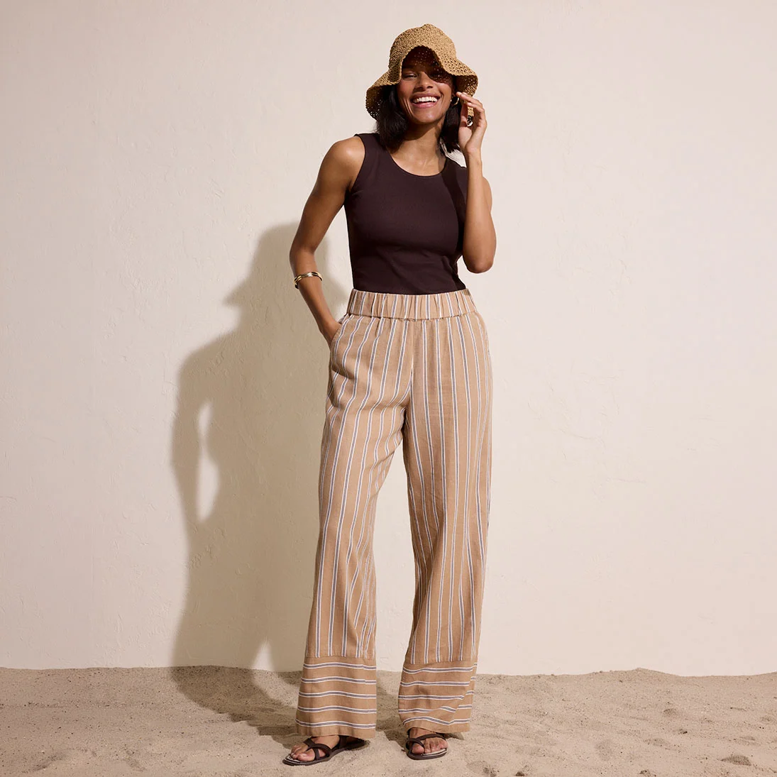 Zwarte top gecombineerd met luchtige, gestreepte broek in warme aardetinten voor een casual zomerlook.