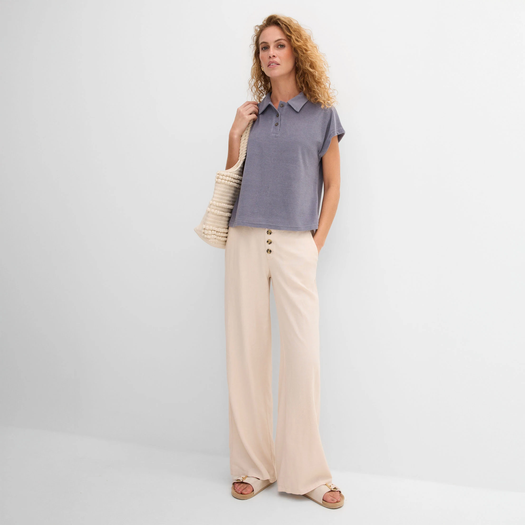 Elegante vrouw draagt blauw, losjes vallend T-shirt en wijde beige broek in casual stijl.