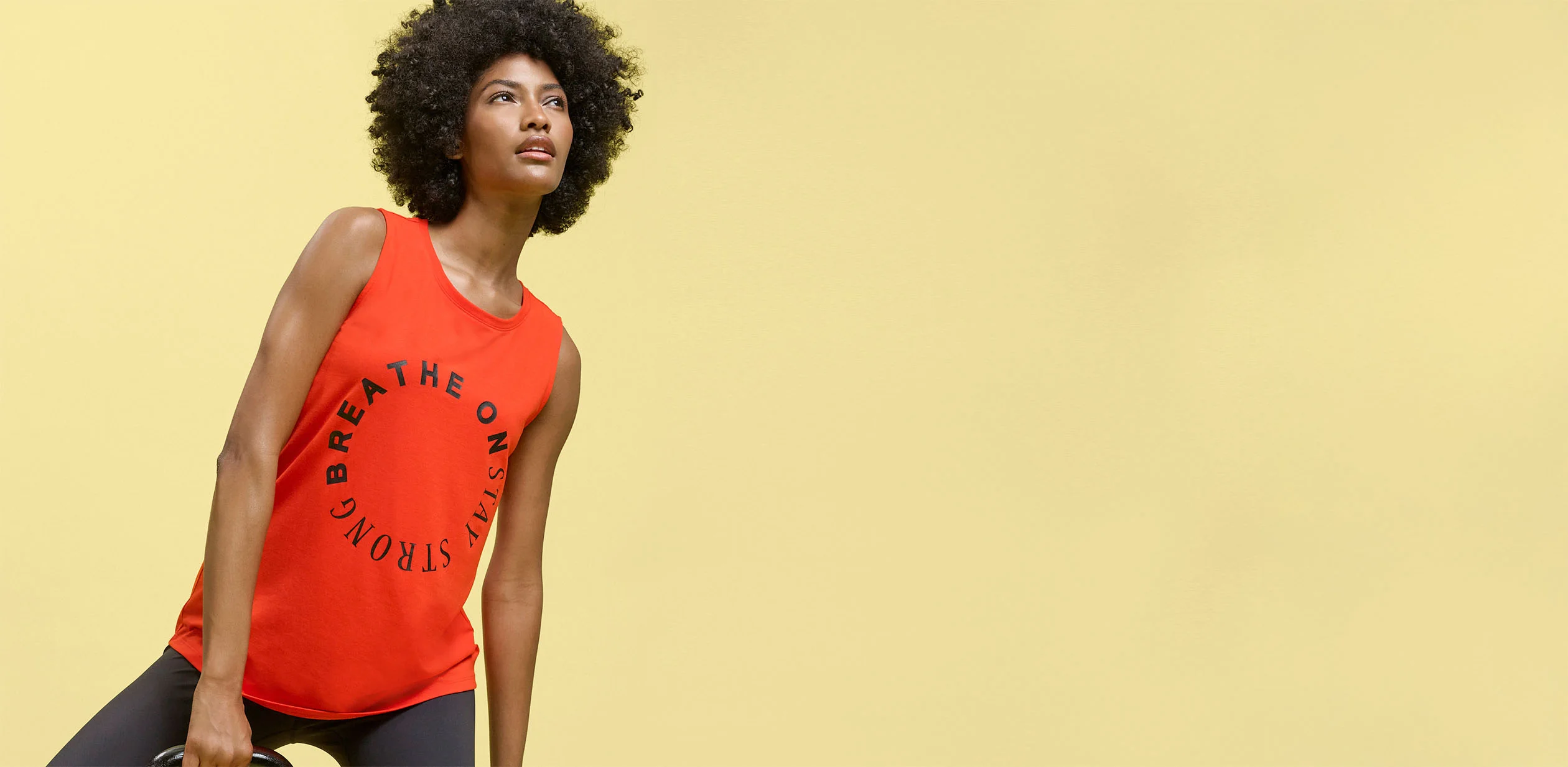 Rode tanktop met tekst "BREATHE ON STAY STRONG" en donkere legging als sportoutfit.