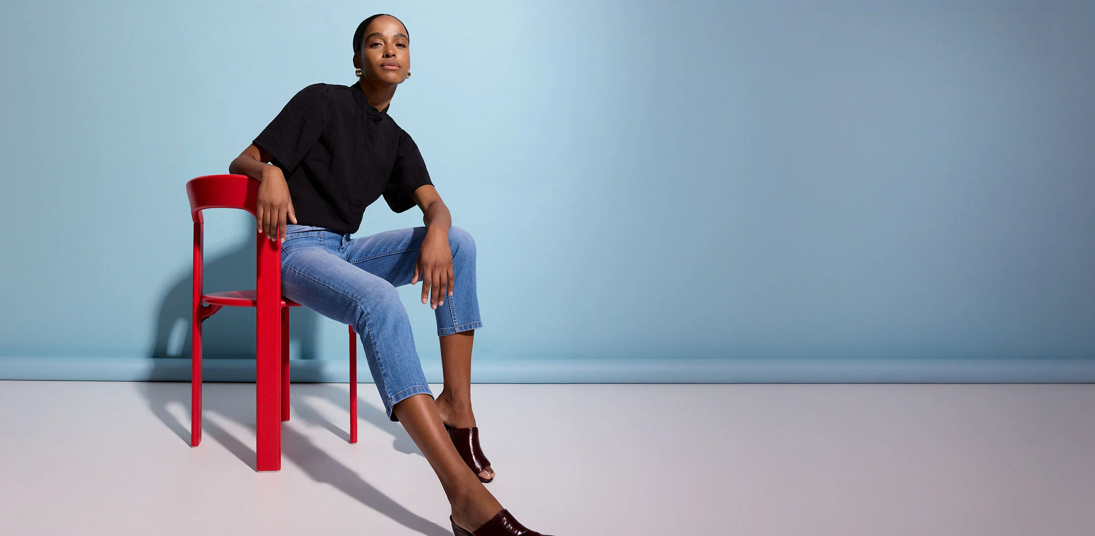 Outfit met zwart shirt, blauwe jeans en glanzende mules.