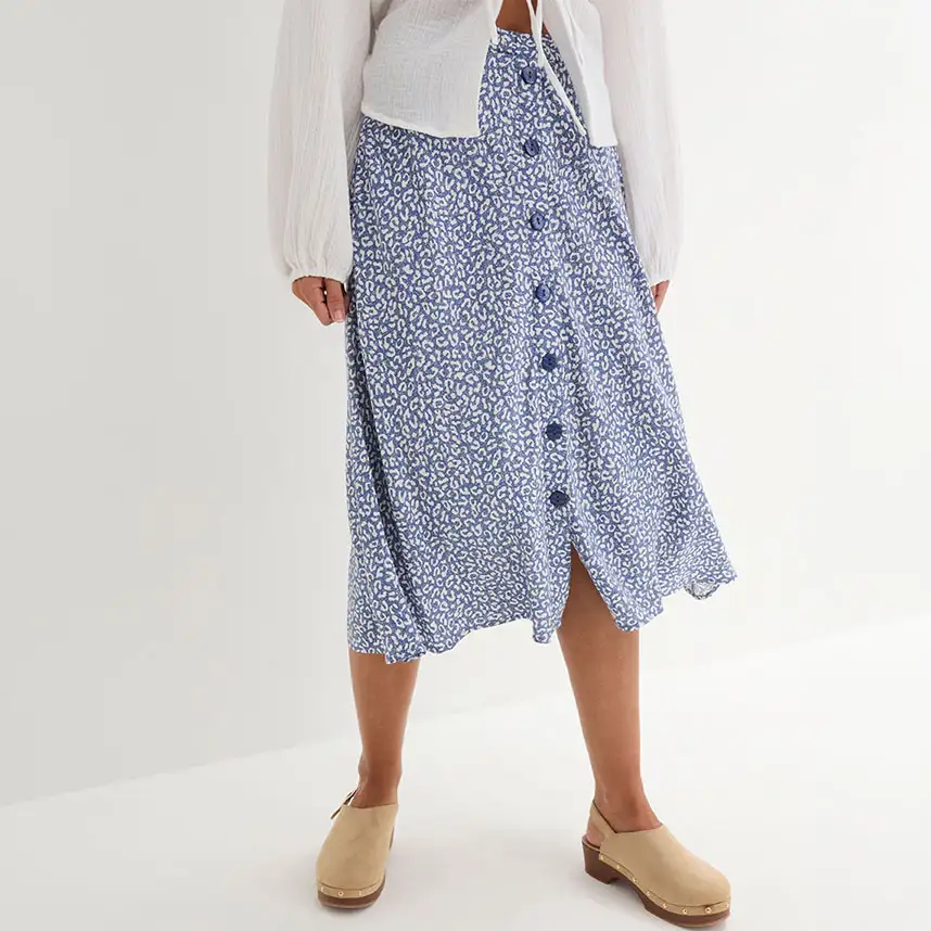 Deze blauwe rok met dessin en knopen past perfect bij de witte blouse en beige clogs.