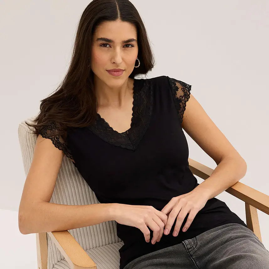 Elegante zwarte top met kant bij de hals, gecombineerd met casual jeans.
