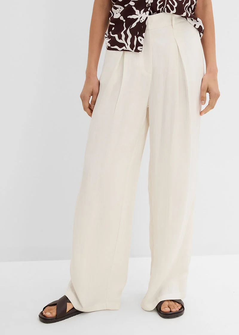 Wijde, lichte broek met plooitjes gecombineerd met gedessineerd shirt en comfortabele sandalen.