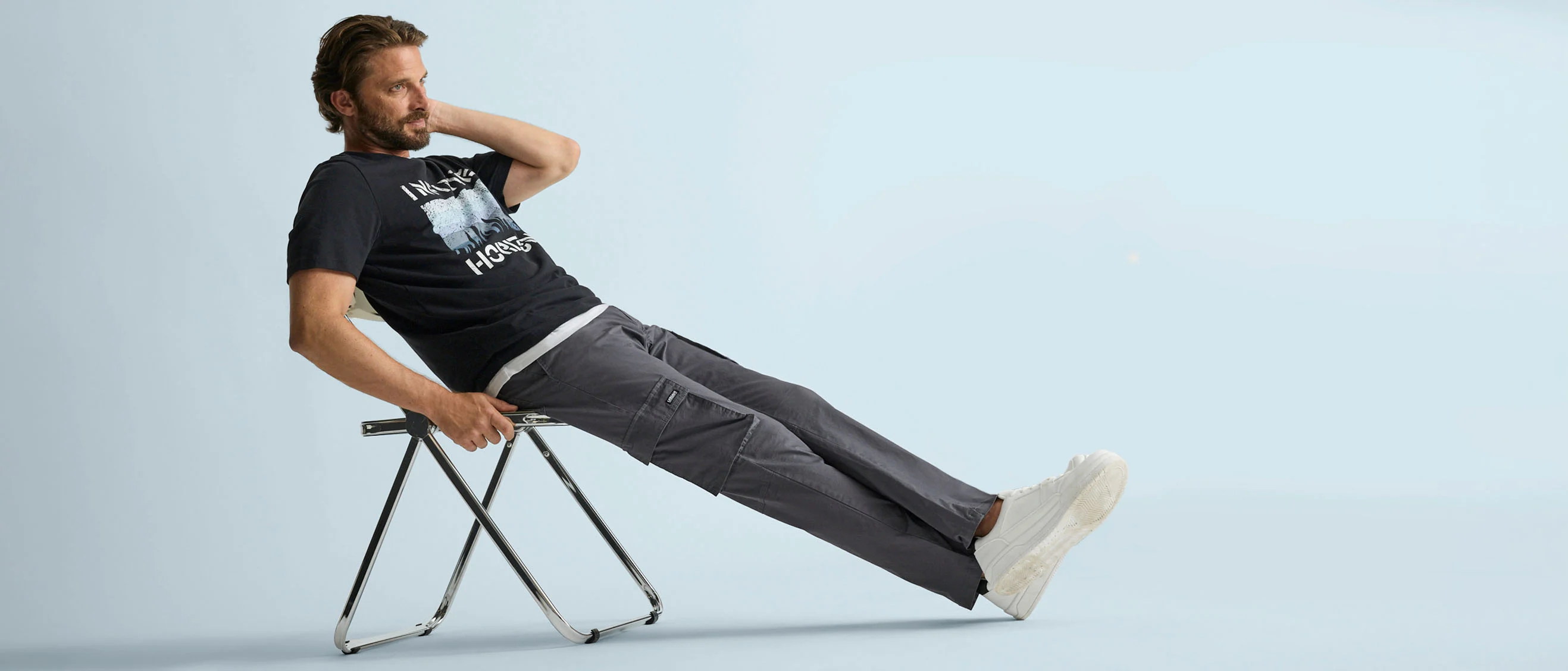 Zwart T-shirt met print, een comfy grijze cargobroek en noncha witte sneakers.