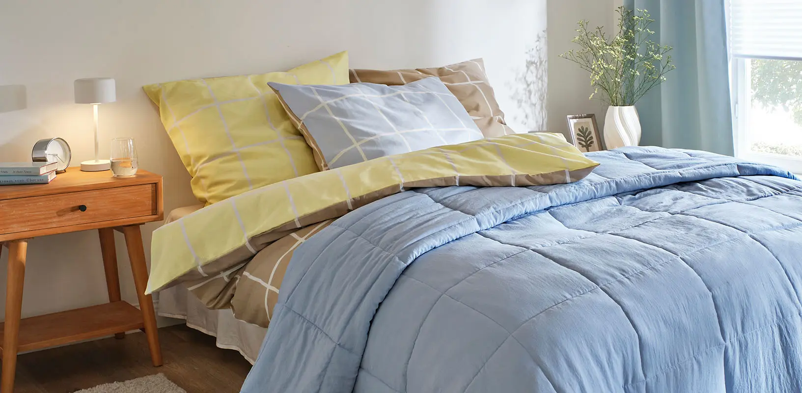 Blauwe sprei, beddengoed met een geel en bruin patroon.