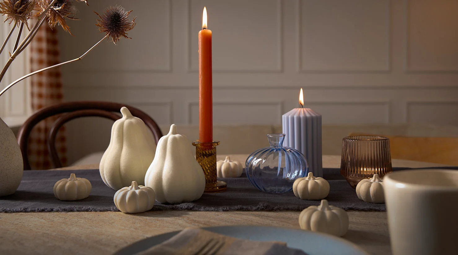 Herfstdecoratie met witte pompoenen en een kaars.