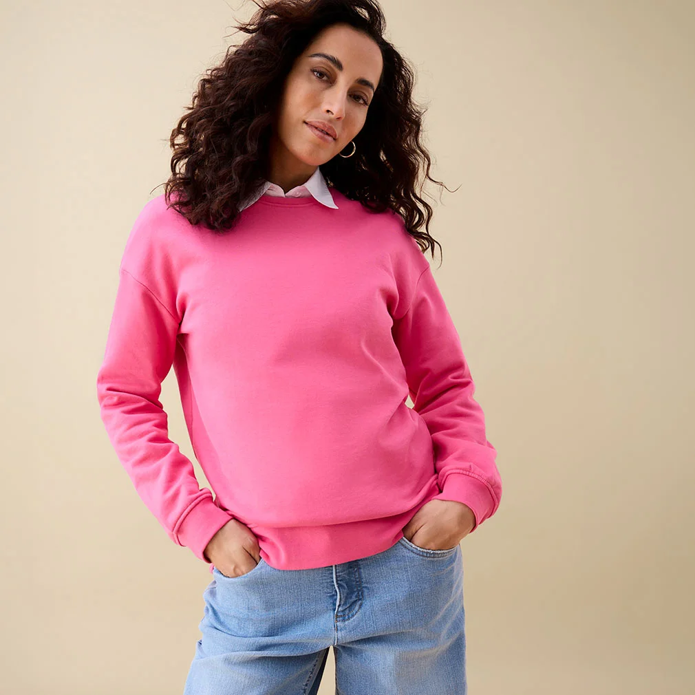 Pink roze sweater over een wit overhemd, gecombineerd met een casual blauwe jeans.