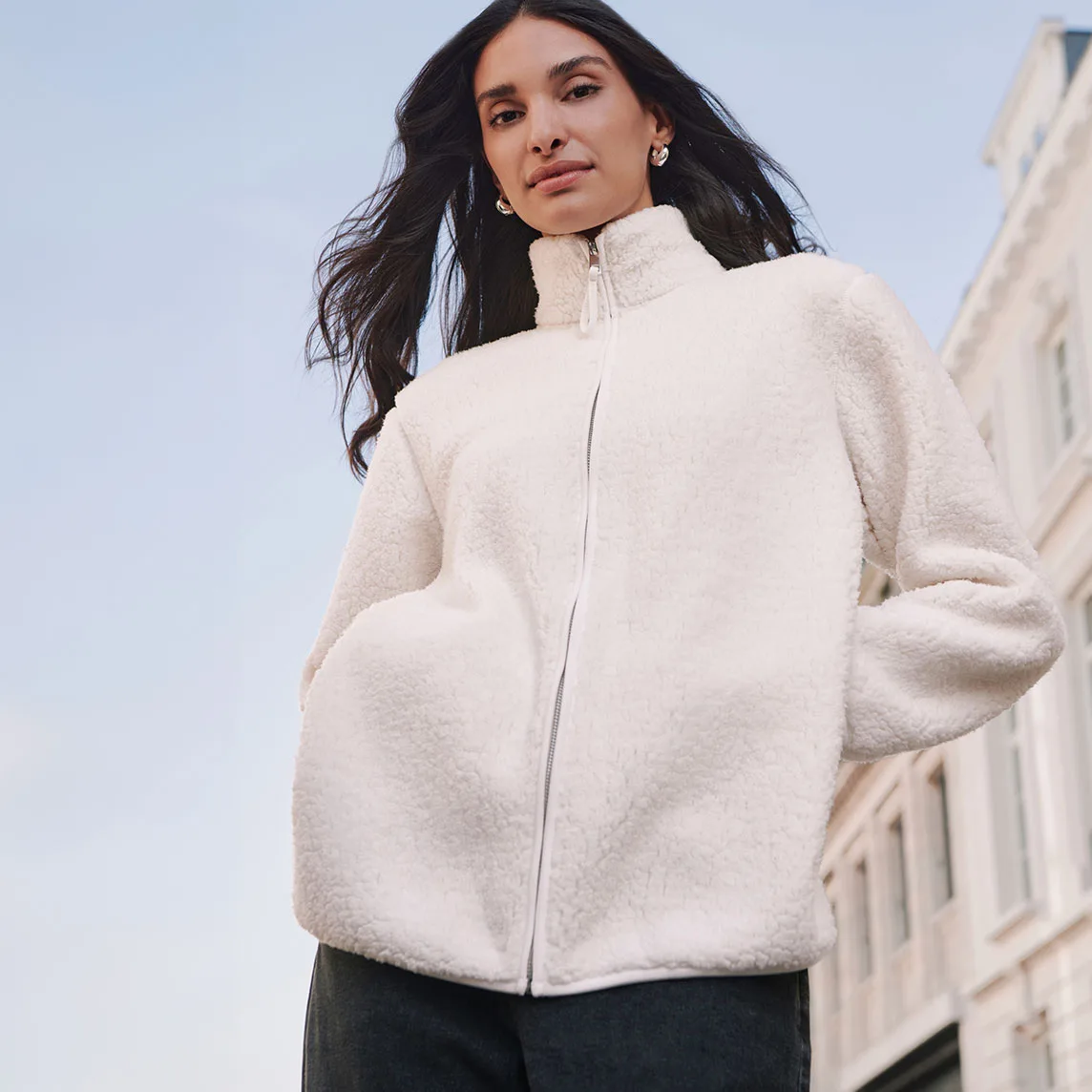 Fluffy crèmekleurig teddy vest met rits en trending donkere broek.