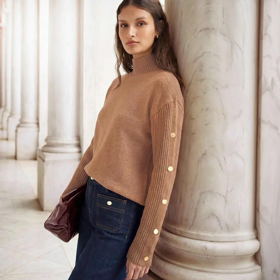 Modieuze coltrui met knoopjes, wijde jeans en elegante tas.