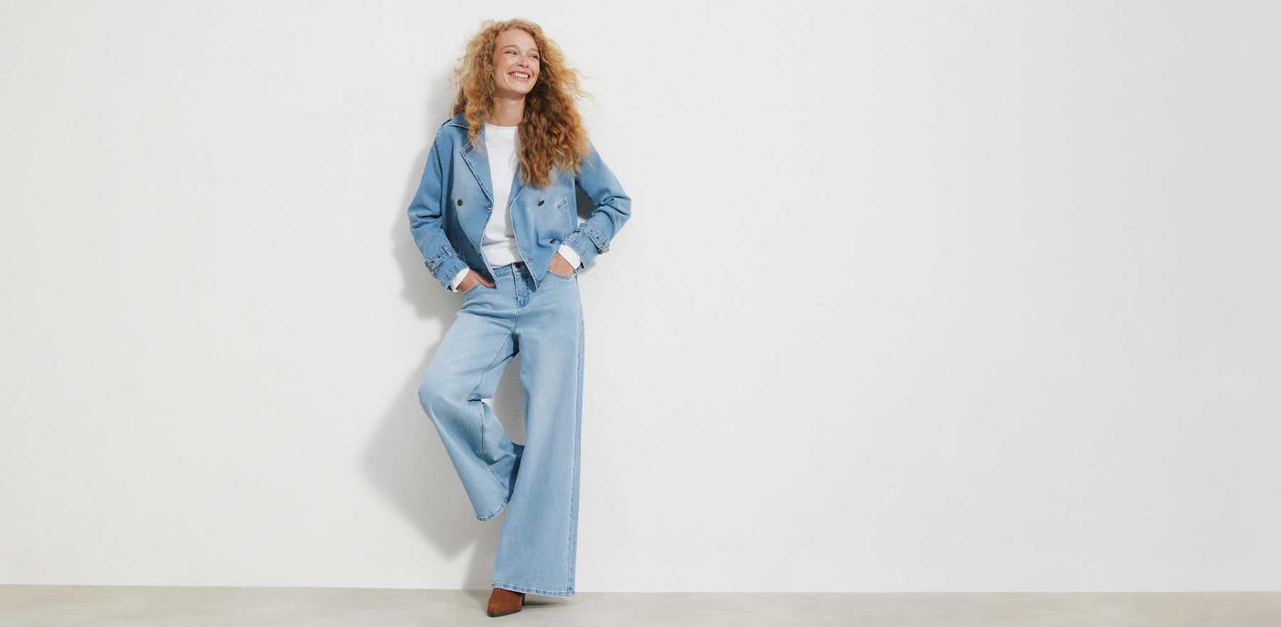 Korte spijkerjas, wijde broek, wit shirt en bruine schoenen.