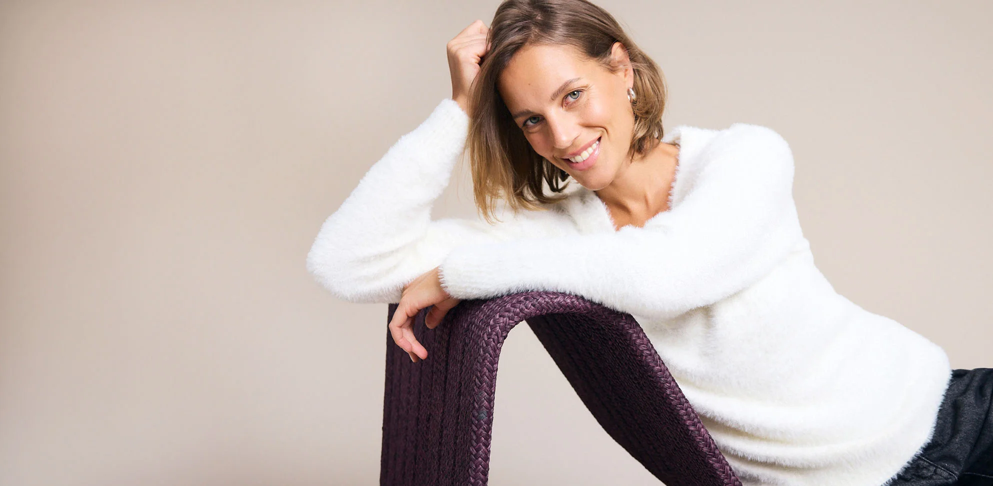 Witte fluffy trui en donkere broek benadrukken de relaxte look.