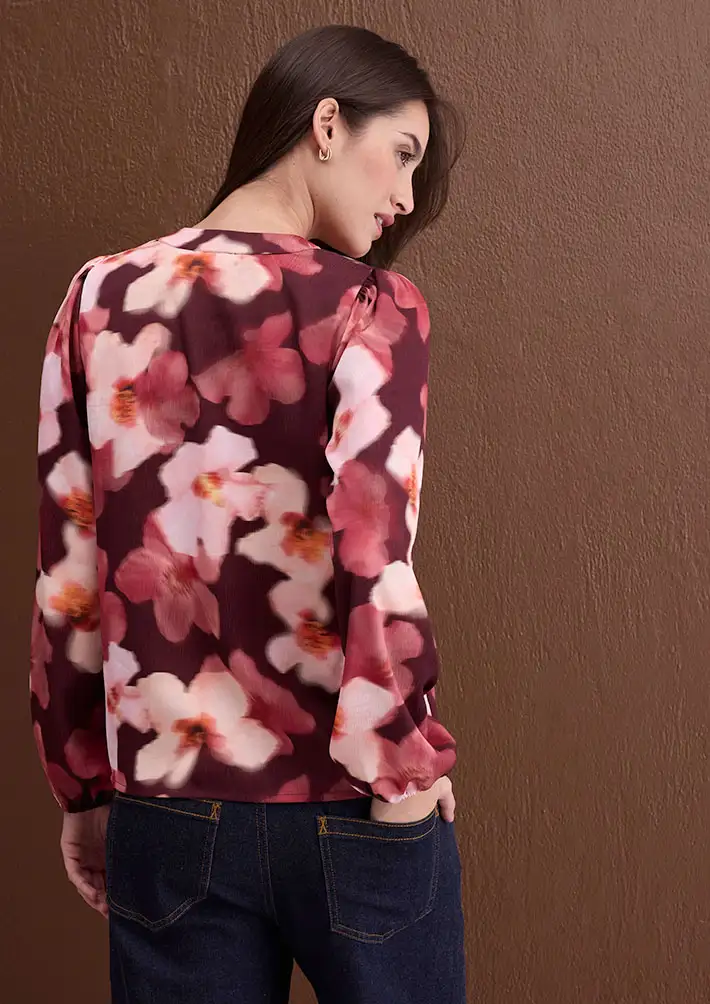 Donkerrode blouse met fijne bloemen, gecombineerd met klassieke blauwe jeans.