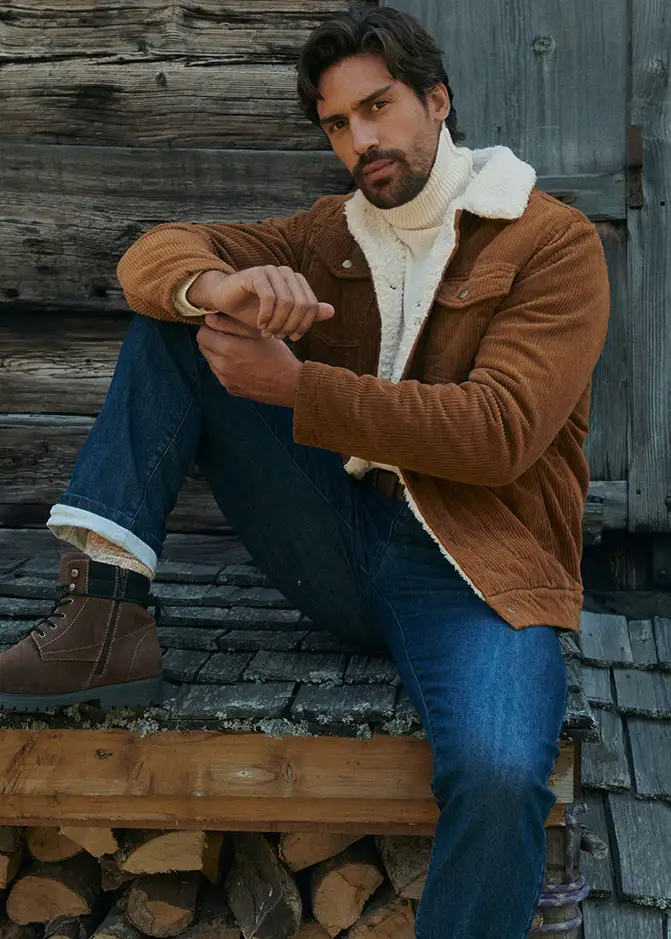 Een bruine corduroy jas, witte coltrui, jeans en gevoerde boots maken de outfit compleet. 